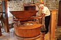 The grain hopper and the wooden vat that encloses the operating millstones.  Expert miller Roland Tetrault at the helm.