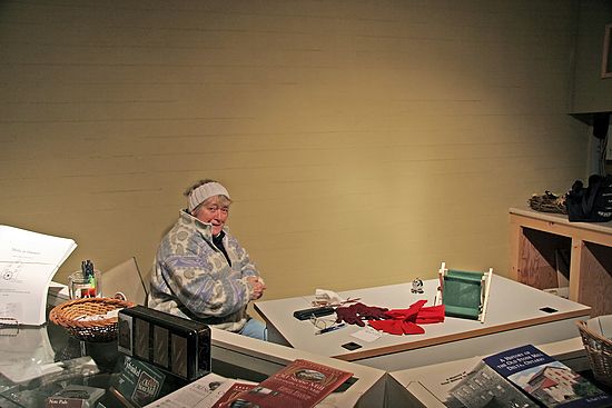 Mary Freiday, director and treasurer of The Delta Mill Society, \nmans the desk in the gift shop/entrance.  Mary is one of \nseveral directors and friends of the Delta Mill who volunteer\n their time to greet visitors on a cold December evening\n (so, pop by and say hello!).
