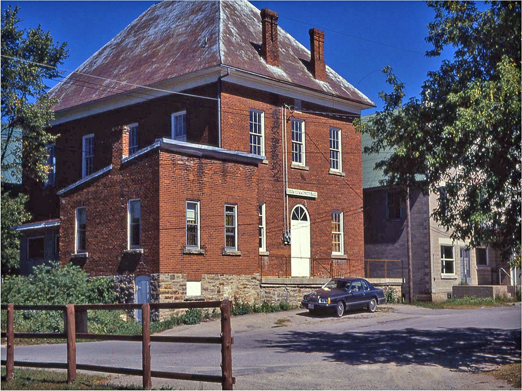 Old Town Hall c.1985.\n\nWe date this photo to about 1985 due to the car parked in front of the building (see below).  Also, the sign "Delta Community Hall" was put up by the Delta Lion's Club who leased the building from the Township of Bastard and South Burgess from about 1979/80 until early 1985 when they relinquished their lease.  \n\nThe car is a 1983-1986 Ford Thunderbird, which, together with the Delta Community Hall signs dates the photo to the mid to late 1980s.